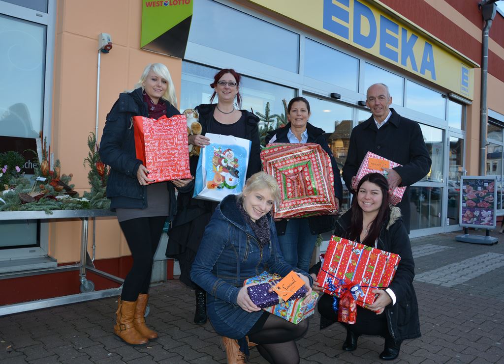 Foto: (stehend v.l.n.r.) Carina Gottschalk, Jennifer Vetter, Ansgar Kieven und Anja Mülln sowie (hockend v.l.) Cindy Röben und Sandra Thönnessen freuen sich über die tolle Resonanz der Wunschbaumaktion und präsentieren eine kleine Auswahl der liebevoll verpackten Geschenke für über 150 Kinder.