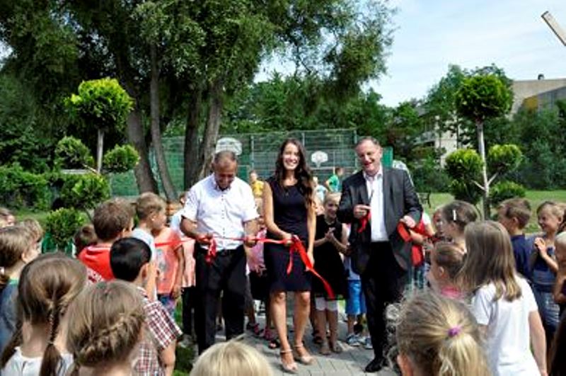 Von links: Edward Schulz, Lena Voth und Bürgermeister Paul Larue durchschnitten das rote Band zur Einweihung des Schulhofes.