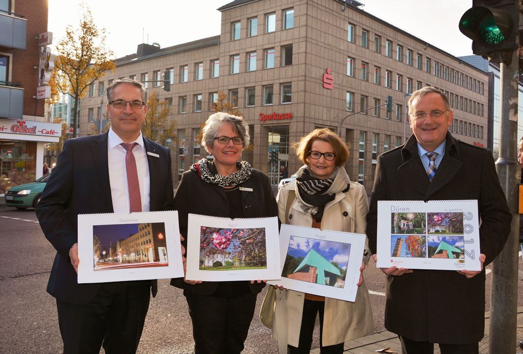 Foto: Mit einem Kalendermotiv im Hintergrund präsentieren (v.l.n.r.) Dirk Hürtgen (Sparkasse Düren), Sabine Briscot-Junkersdorf (Stadt Düren, Marketing), Claudia Latotzki und Bürgermeister Paul Larue den neuen Düren-Kalender 2017.