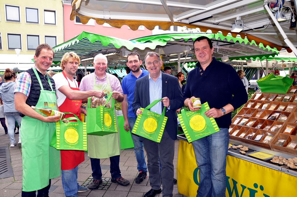 Wochenmarktbeschicker Klaus Langen, Oliver Hintzen, Hans-Georg Pohl, Roland Lentzen und Frank Schmutzler(rechts), Vorsitzender des „Fördervereins Dürener Wochenmarkt“, zeigen Bürgermeister Paul Larue (2.von rechts) die Vorteile der Wochenmarkt-Tasche.