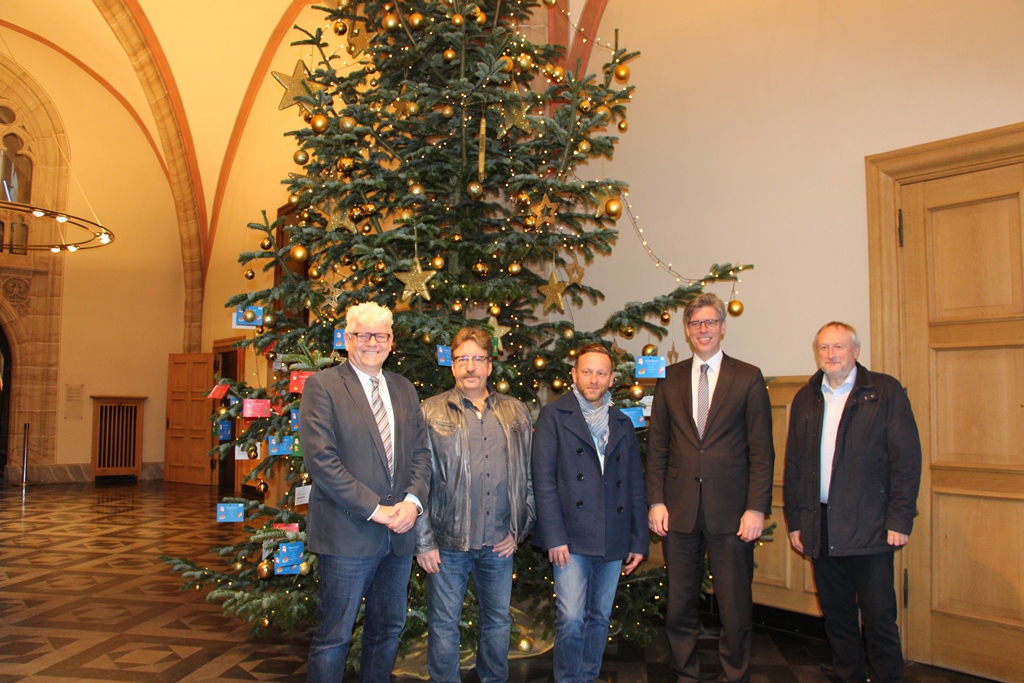 Für OB Marcel Philipp (2.v.r.) sowie (v.r.n.l.) Stefan Küpper, Burkhard Büttgen und Horst Kreutz von den beteiligten Jugendhilfeeinrichtungen und André Schnitker, Referent des Oberbürgermeisters und Organisator der Aktion, ist das Treffen am Wunschzettelweihnachtsbaum im Rathausfoyer ein Highlight in der Vorweihnachtszeit.  Foto: Stadt Aachen