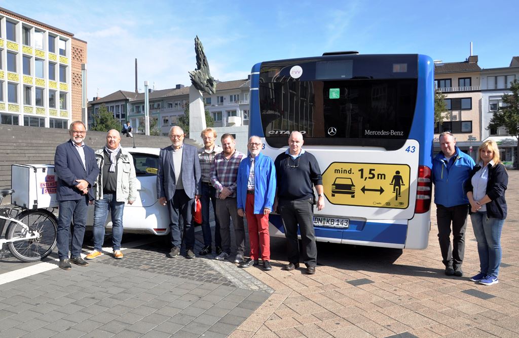 : Gelber Aufkleber auf blau-weißem Bus - Organisatoren und Unterstützer bei der Vorstellung der Seitenabstandskampgane auf dem Rathausvorplatz.  Foto: Stadt Düren.