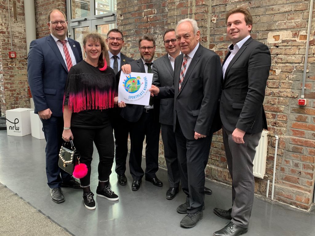 Gruppenbild am Rande der Veranstaltung zum Projektstart mit v.l.n.r. Bürgermeister Manuel Deitert (Gemeinde Reken), Staatssekretärin Andrea Milz, BM Ralf Claßen, Dr. Jan Fallack (StGB NRW), N.N., Präsident Walter Schneeloch (LSB NRW), Vizepräsident Jens Wortmann (LSB NRW) 