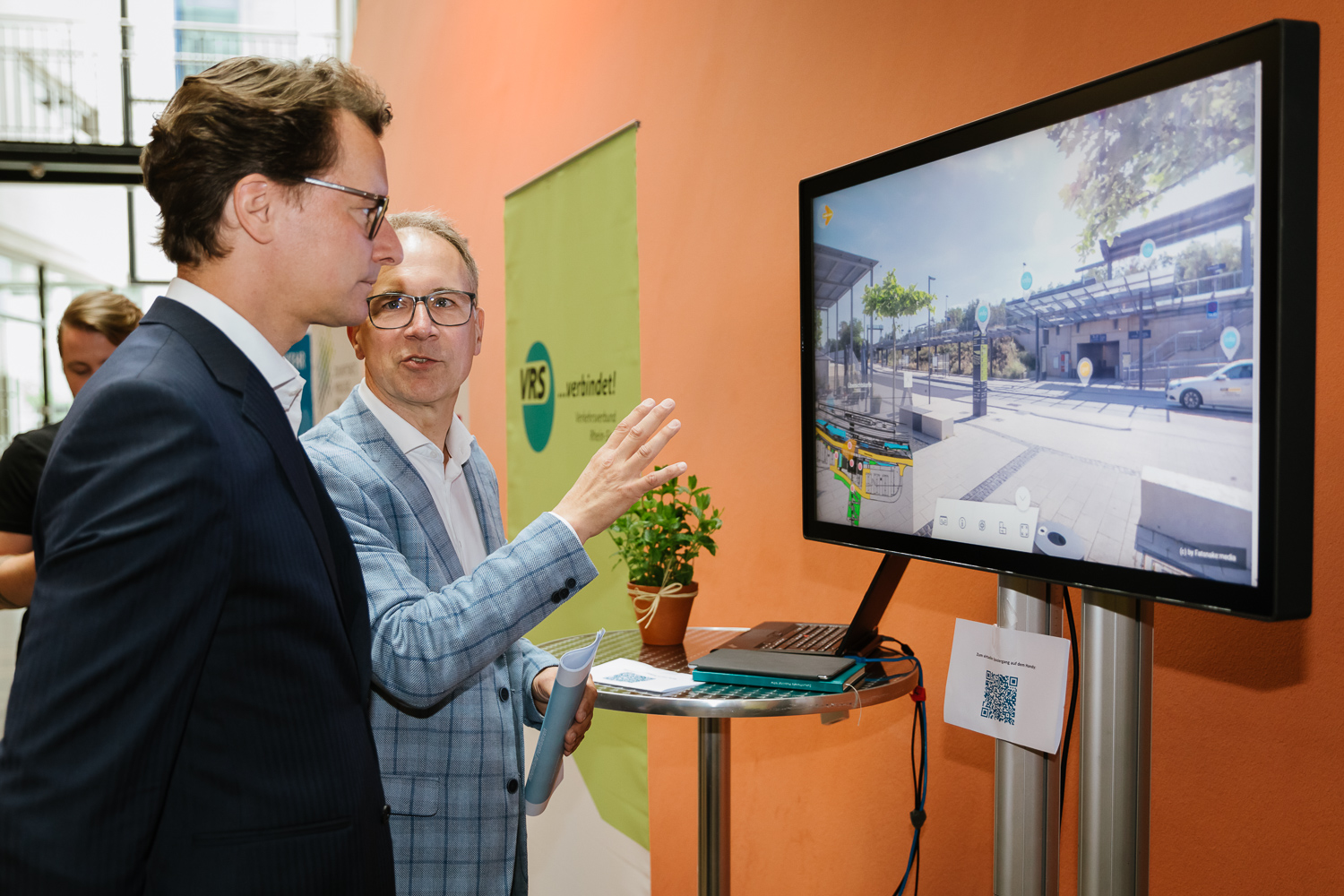 Dr. Norbert Reinkober (Geschäftsführer Nahverkehr Rheinland) erläutert Landesverkehrsminister Hendrik Wüst den virtuellen Spaziergang durch die Mobilstation in Erftstadt. Credits: NVR/Smilla Dankert