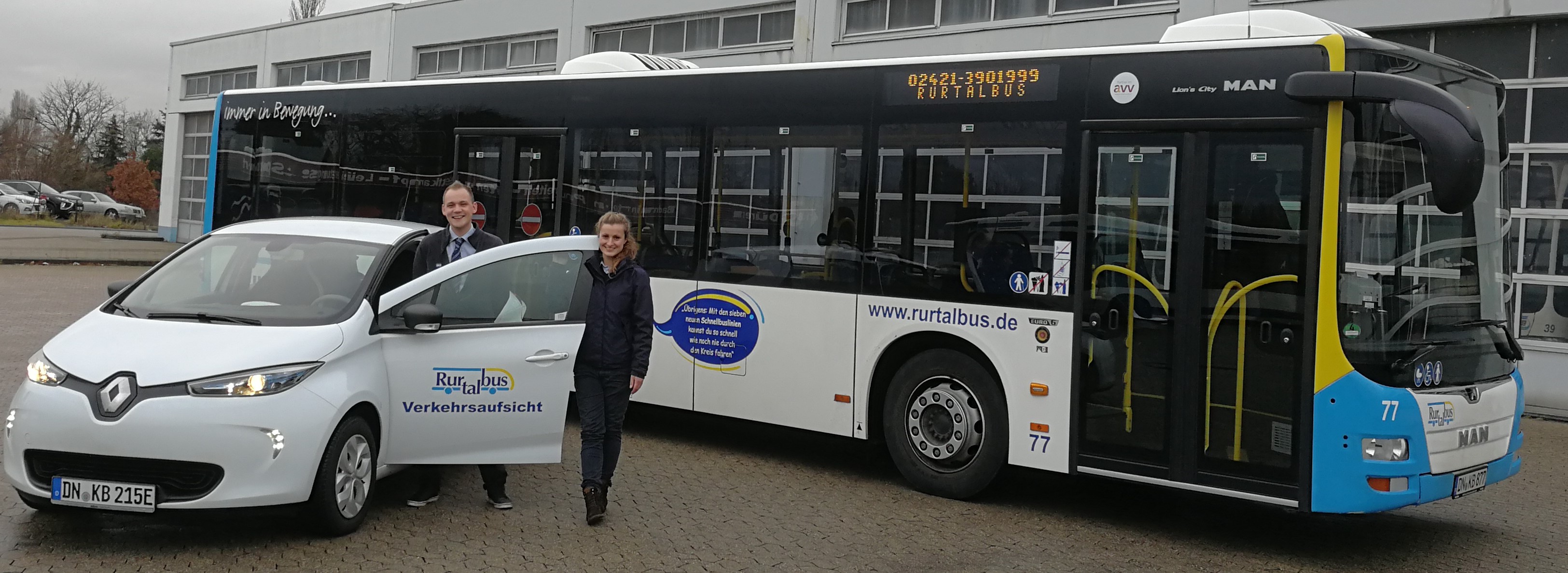 Auszubildende Maren Schießl und Sebastian Arndt (Disposition) vor dem E-Auto, das die Rurtalbus unter anderem für Fahrerwechsel in ihren Bussen einsetzt. Foto: Rurtalbus