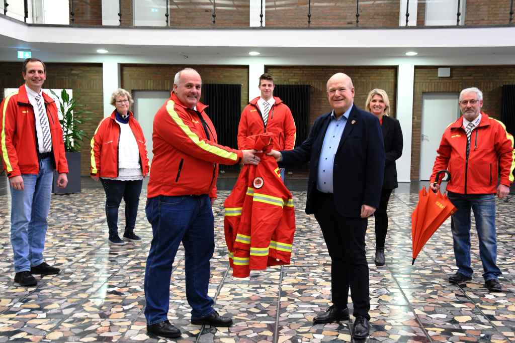 Schirm und Jacke für den neuen Schirmherrn: Zusammen mit Vertreterinnen und Vertretern des Vorstands der Ortsgruppe Düren übergab der Stellvertretende Vorsitzende, Richard Bergsch, eine DLRG-Jacke an Bürgermeister Frank Peter Ullrich.
