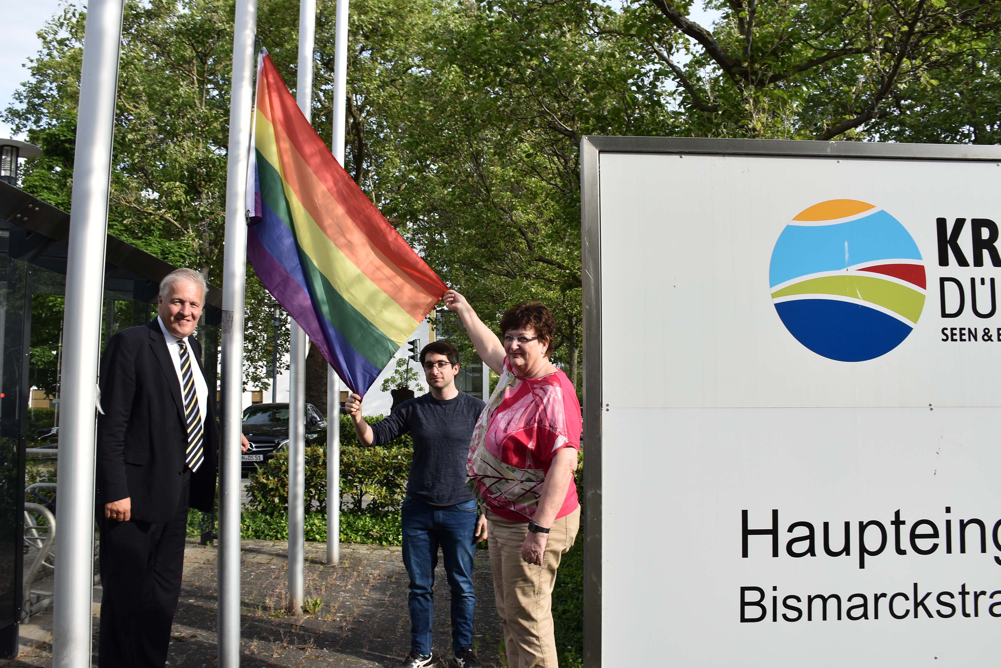 : Landrat Wolfgang Spelthahn, Giacomo Klingen und Gudrun Zentis (beide von der Grünen-Kreistagsfraktion) hissen die Regenbogenflagge. Foto: Kreis Düren