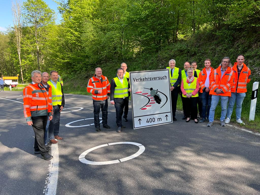 NRW-Verkehrsminister Oliver Krischer (am Schild links), Landrat Wolfgang Spelthahn (am Schild rechts), Straßen.NRW Direktor Dr. Sascha Kaiser (links neben Oliver Krischer) und weitere Verantwortliche machten sich heute persönlich ein Bild von den neuen Streckenmarkierungen auf der L218 ("Panoramastraße") in der Gemeinde Hürtgenwald, die für mehr Verkehrssicherheit sorgen sollen. Foto: Kreis Düren