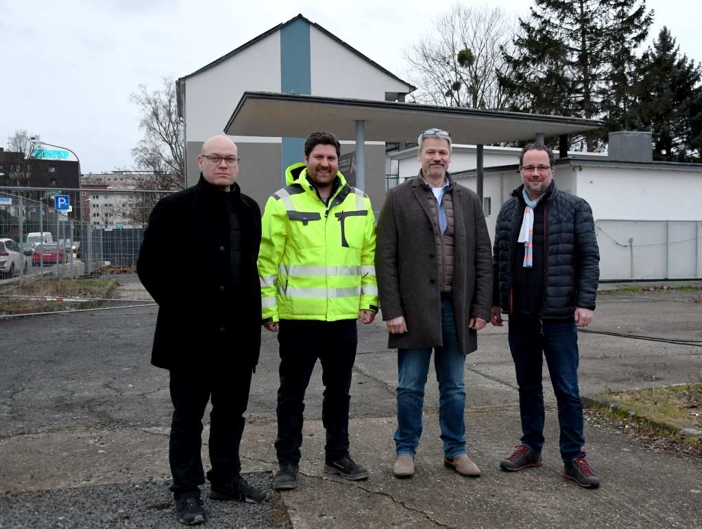 Foto: (v.l.n.r.) Baudezernent Niels-Christian Schaffert, Tobias Anderson (Amt für Gebäudemanagement), Hans-Willi Schroeder (Leiter Amt für Gebäudemanagement) und Tobias Marks (stellvertretender Leiter Amt für Gebäudemanagement) vor der ehemaligen Tankstelle auf der Arnoldsweilerstraße, die jetzt abgerissen wird.