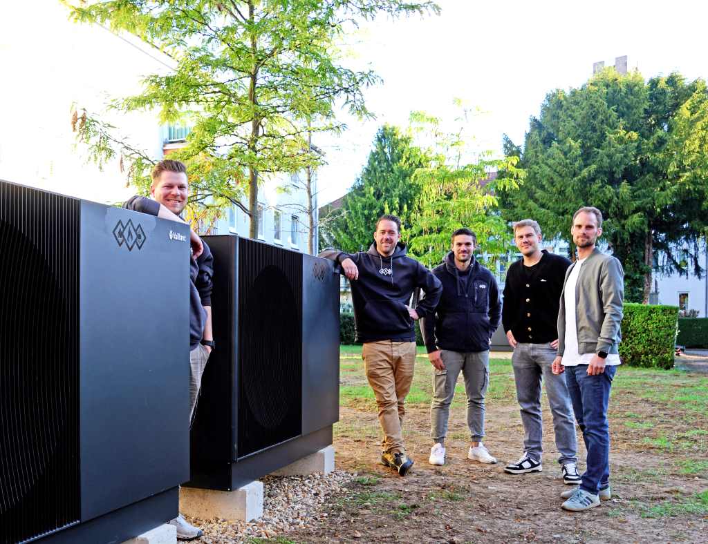 Die Verantwortlichen von Dürener  Bauverein und Inwateck an den gro ßen Wärmepumpen im Garten der  Häuser Steinweg 7 und 9.  Foto: C. Lammertz / ZieL.media